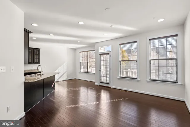 a large living room with stainless steel appliances wooden floor and a large window