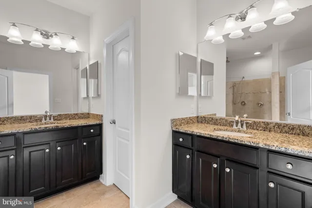 a bathroom with a granite countertop double vanity sink and a mirror