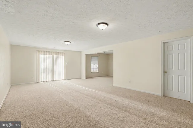 a view of an empty room with window and closet area