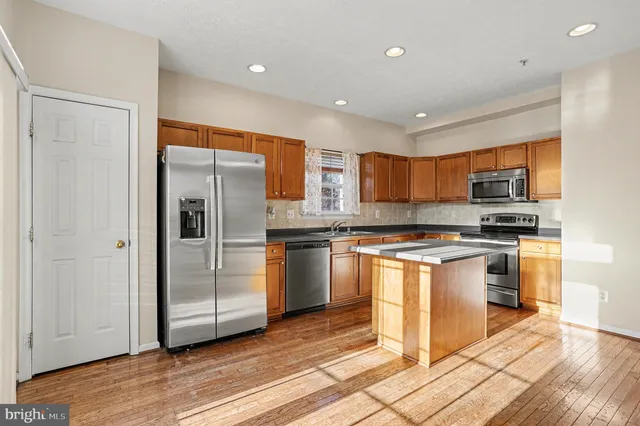 a kitchen with stainless steel appliances granite countertop a refrigerator and a stove top oven