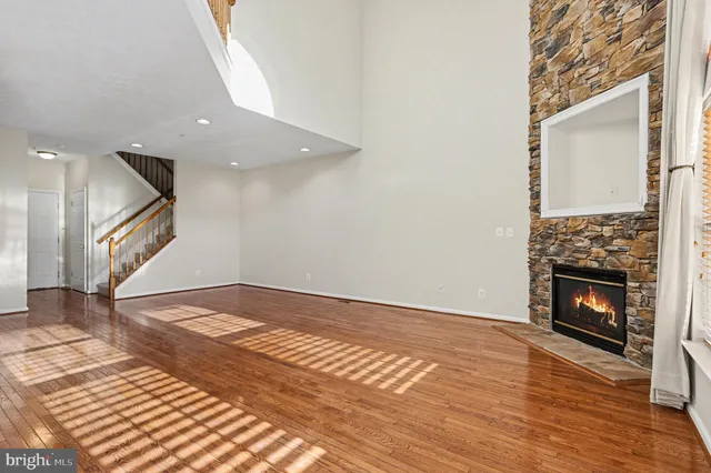 a view of an empty room with wooden floor fireplace and a window