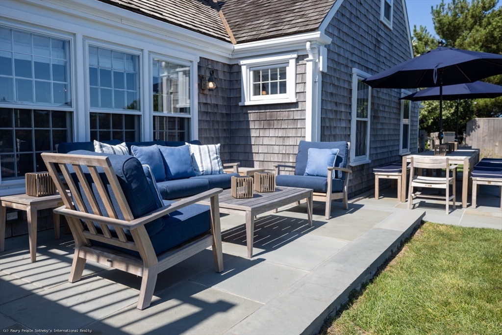 21 Quidnet Road, Unit 1 Nantucket, MA 02554 - Photo 7 of 42 a view of a patio with table and chairs with wooden floor and fence