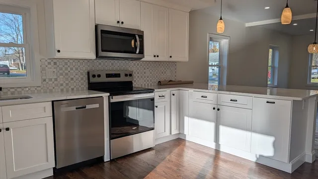 a kitchen with cabinets stainless steel appliances and wooden floor