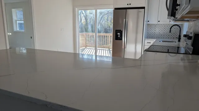 a view of kitchen with granite countertop cabinets and refrigerator