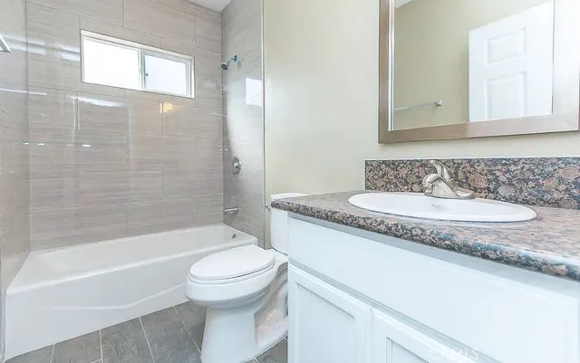 a bathroom with a granite countertop sink a toilet and a bathtub