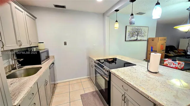 a kitchen with granite countertop a sink a stove and refrigerator