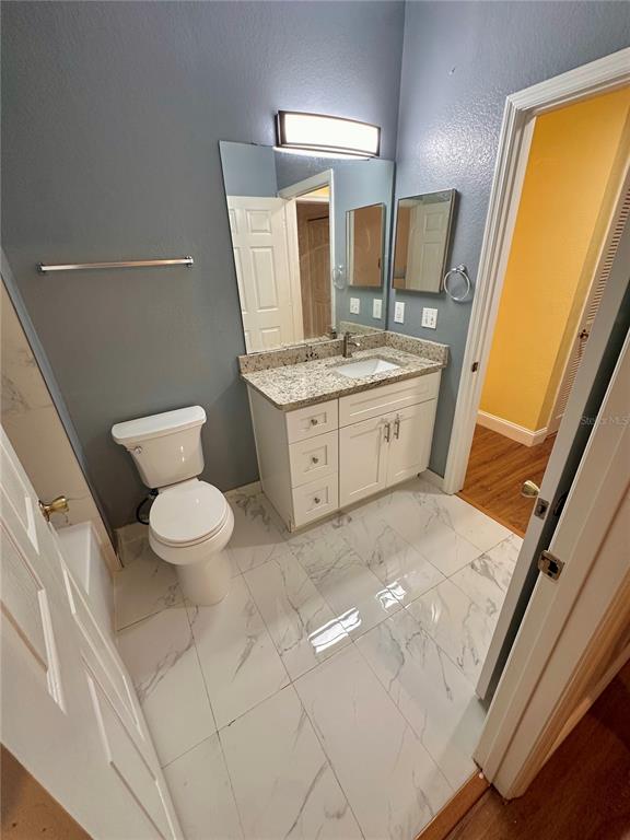 3280 Soho Street, Unit 308 Orlando, FL 32835 - Photo 30 of 45 a bathroom with a granite countertop sink toilet and mirror