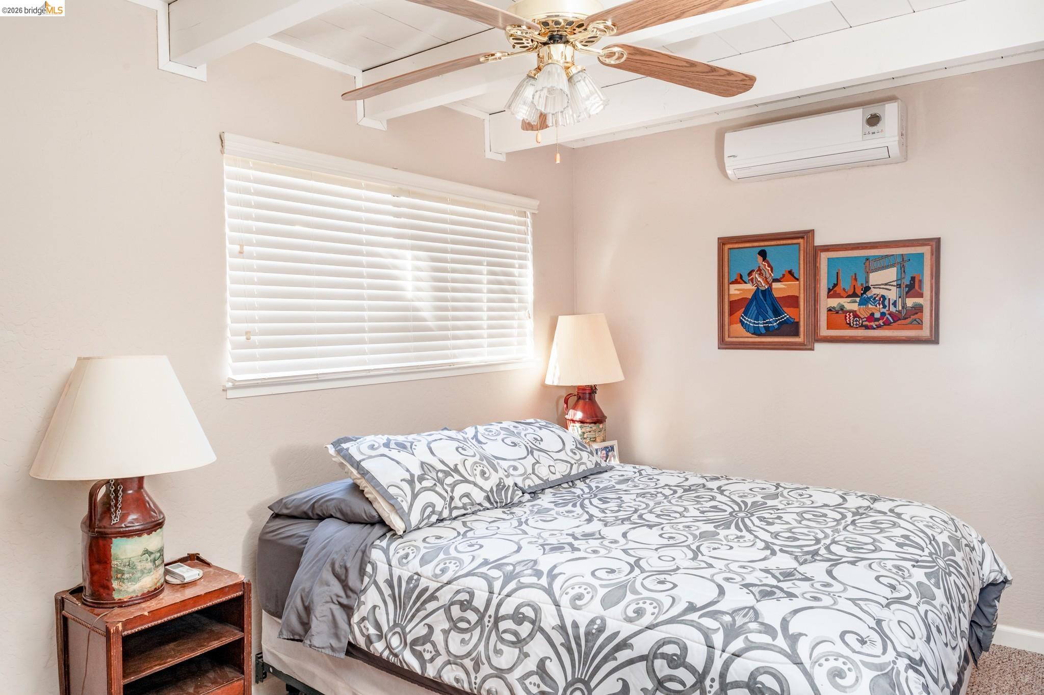 19711 Pleasantview Drive Groveland, CA 95321 - Photo 20 of 39 Room featuring exposed ceiling beams, a window with blinds, ceiling fan, and wall-mounted air conditioning unit