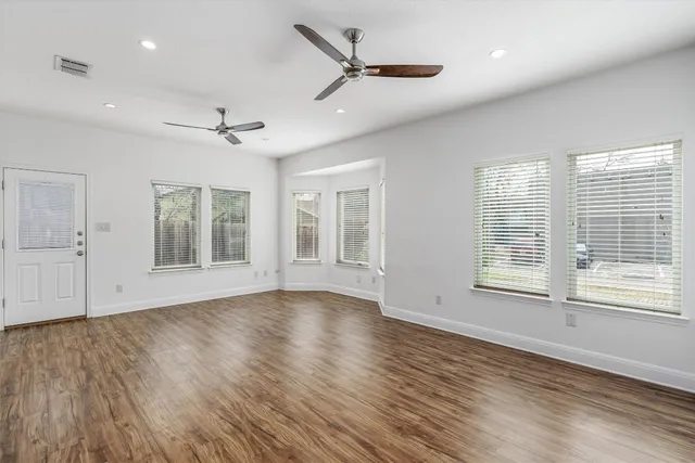 a view of an empty room with a window and wooden floor