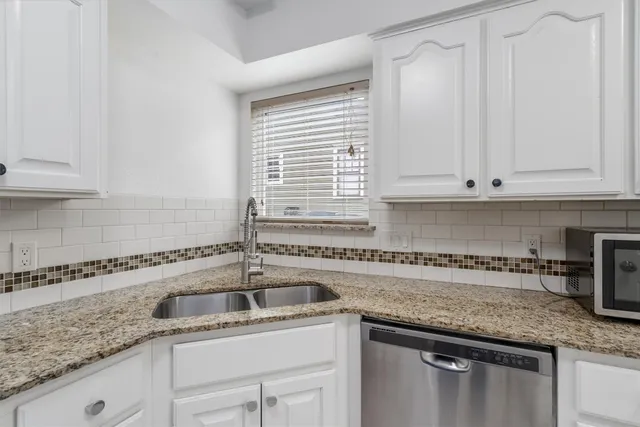 a kitchen with granite countertop a sink and white cabinets