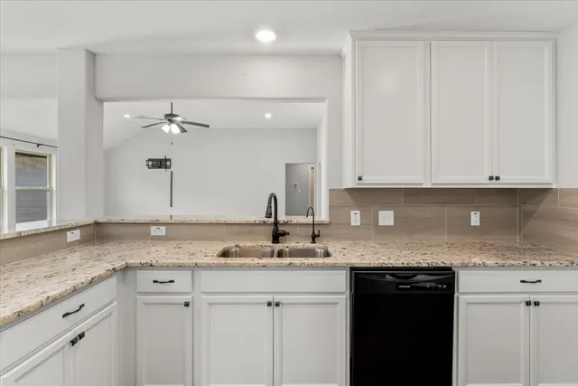 a kitchen with granite countertop white cabinets and stainless steel appliances
