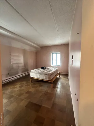 a bed sitting in a spacious bedroom next to a window and dresser