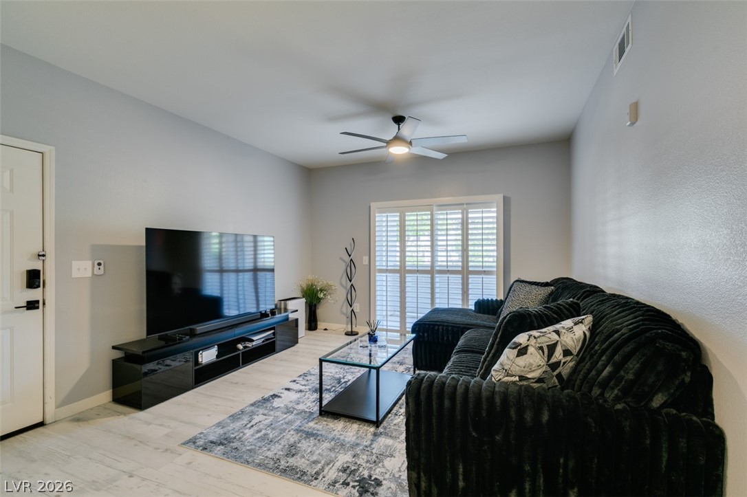 7255 West Sunset Road, Unit 1103 Las Vegas, NV 89113 - Photo 12 of 35 A well-lit living area features neutral tones and a functional ceiling fan for comfort.