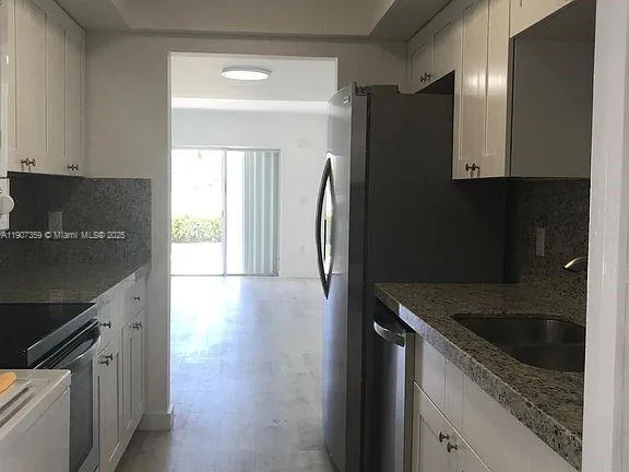 a kitchen with granite countertop a refrigerator and a sink