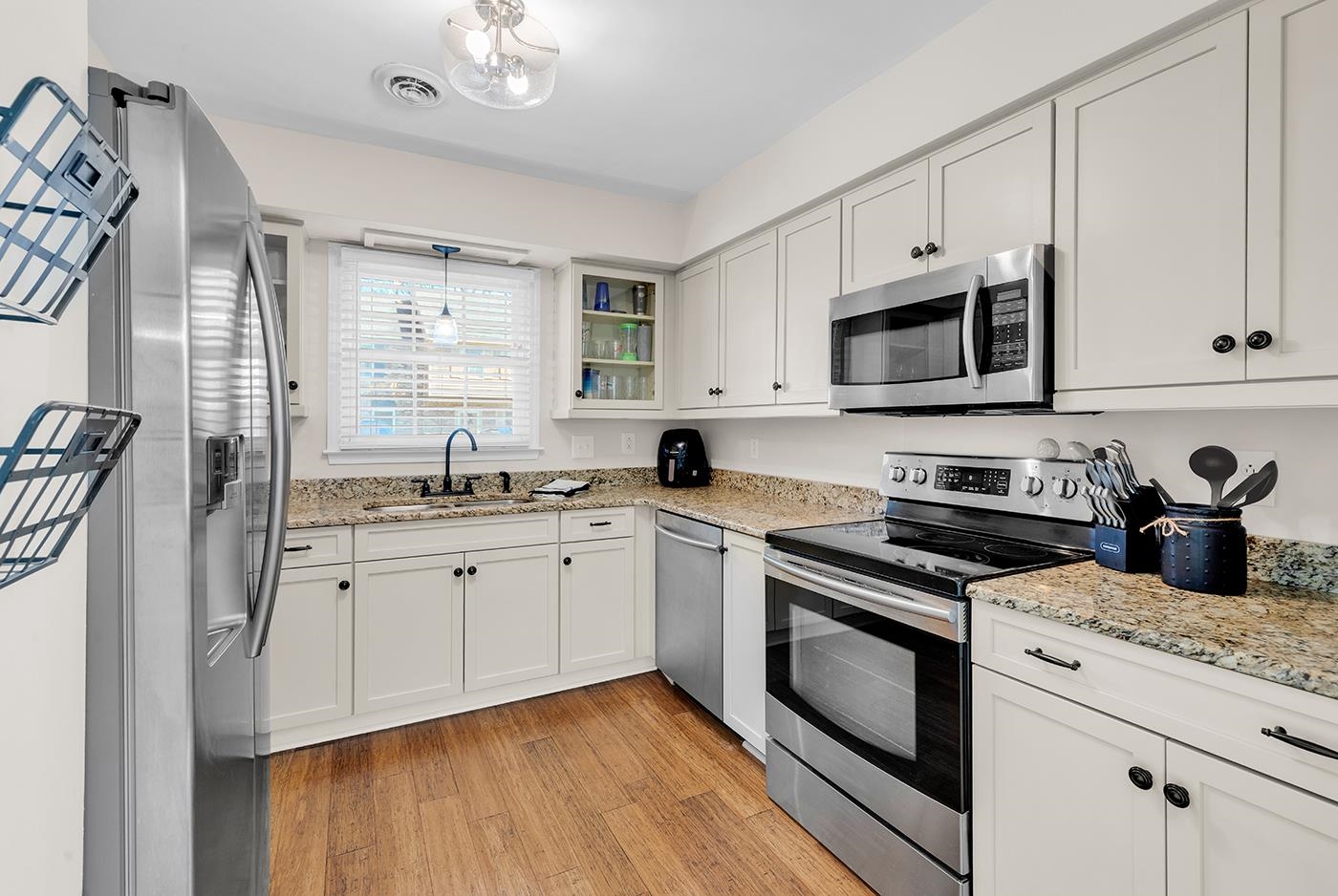 830 44th Avenue North, Unit L1 Myrtle Beach, SC 29577 - Photo 16 of 40 Kitchen featuring appliances with stainless steel finishes, glass insert cabinets, light stone counters, and white cabinetry