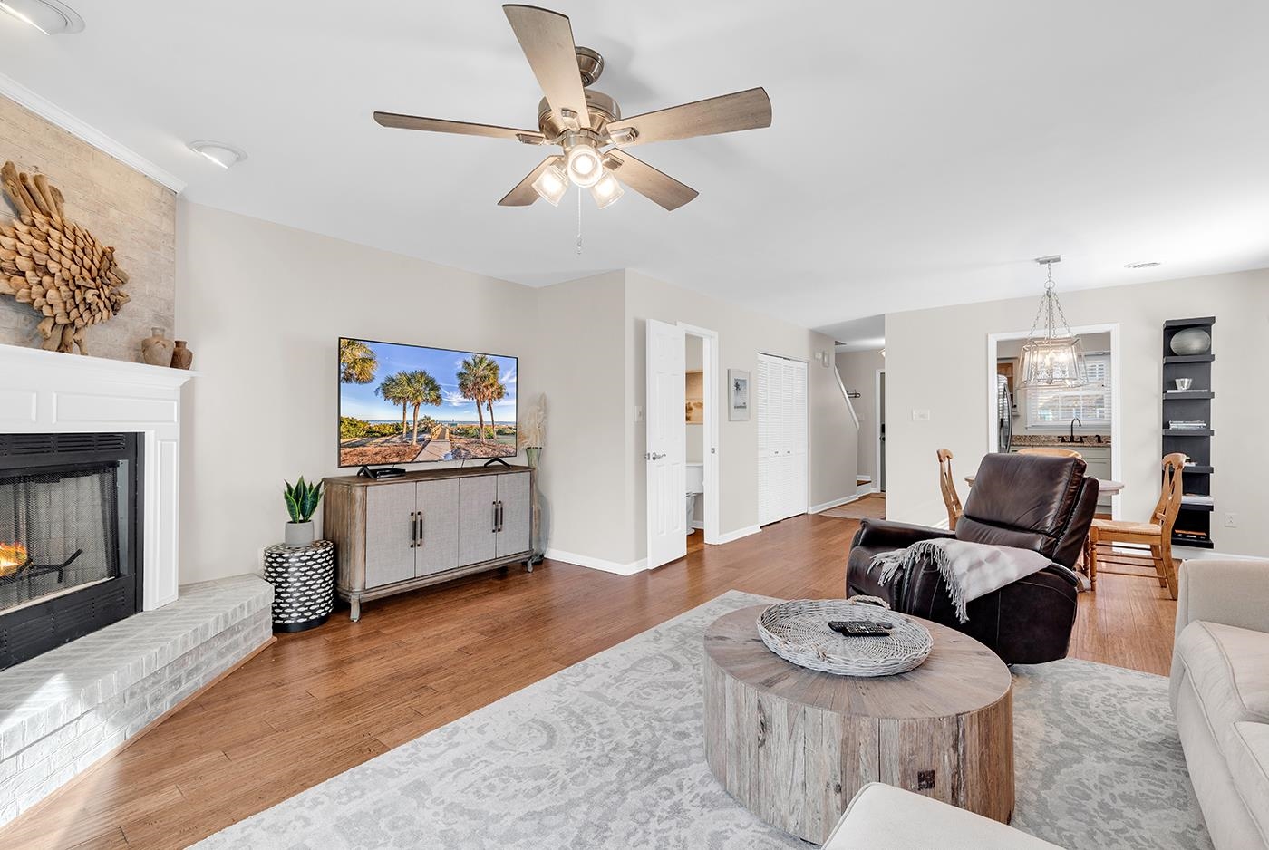 830 44th Avenue North, Unit L1 Myrtle Beach, SC 29577 - Photo 9 of 40 Living room featuring wood finished floors, a warm lit fireplace, a ceiling fan, and a chandelier