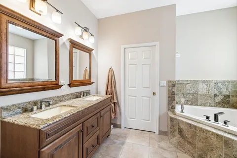 a spacious bathroom with a tub sink and mirror
