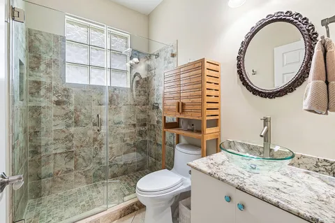 a bathroom with a granite countertop toilet a sink and a mirror