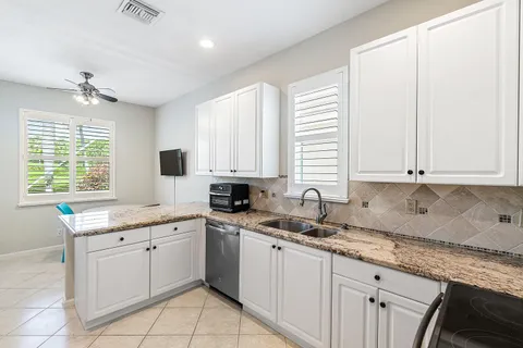 a kitchen with a sink dishwasher a stove and white cabinets