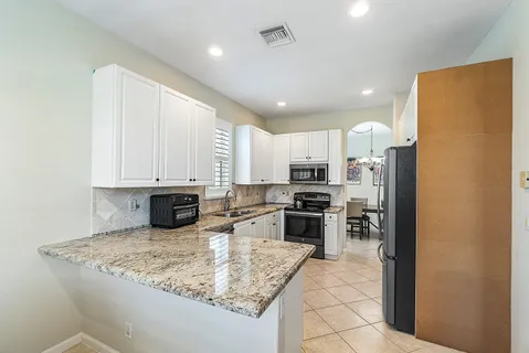 a kitchen with stainless steel appliances granite countertop a sink refrigerator and cabinets
