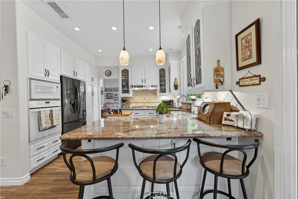 17 Vía Anadeja Rancho Santa Margarita, CA 92688 - Photo 19 of 43 a kitchen with stainless steel appliances kitchen island granite countertop a dining table chairs and sink