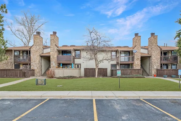 a view of a white house with a big yard and large trees