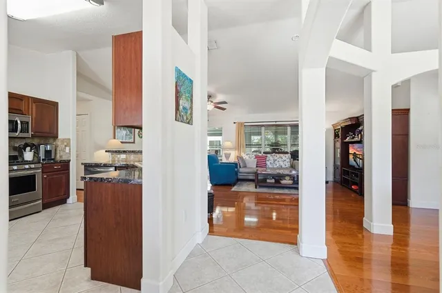 a kitchen with stainless steel appliances granite countertop a refrigerator and a view of living room