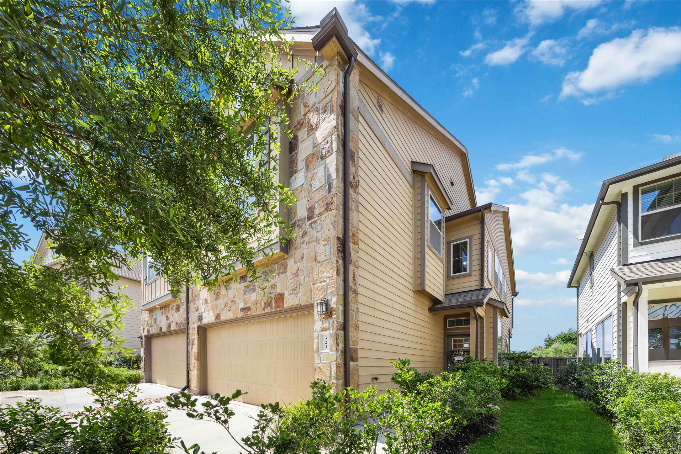 323 Biltmore Loop Montgomery, TX 77316 - Photo 2 of 27 Side view of the home with stone and siding exterior, lush landscaping, and private fenced backyard access.