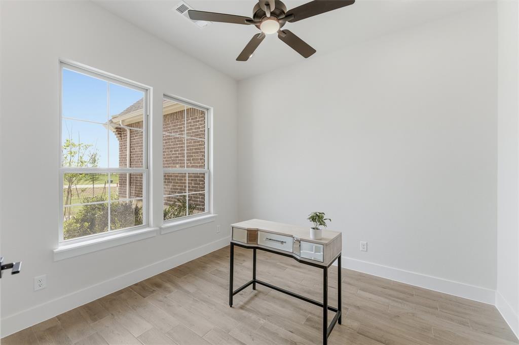 2433 Meteor Drive Krum, TX 76249 - Photo 5 of 29 Bright interior space featuring two large windows, wood-finish flooring, crisp white walls, and a ceiling fan with integrated lighting
