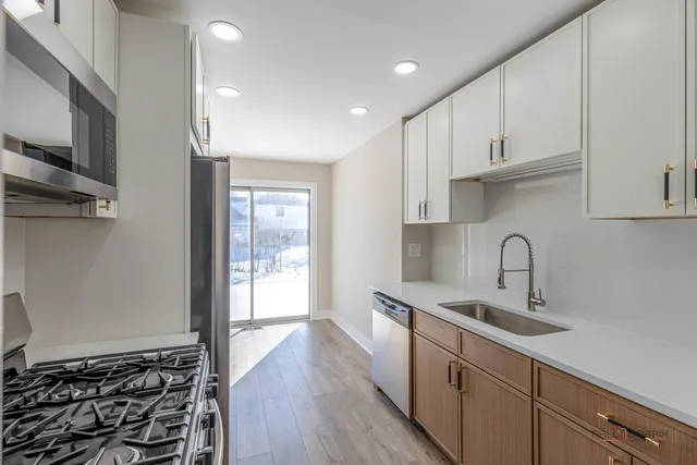 a kitchen with stainless steel appliances granite countertop a sink and wooden cabinets