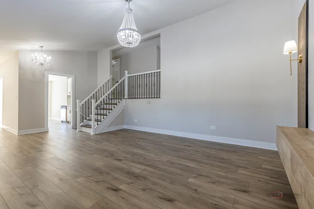a view of an empty room with wooden floor and stairs