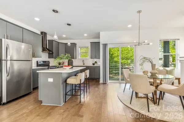 a kitchen with stainless steel appliances granite countertop a refrigerator a sink a stove a dining table and chairs