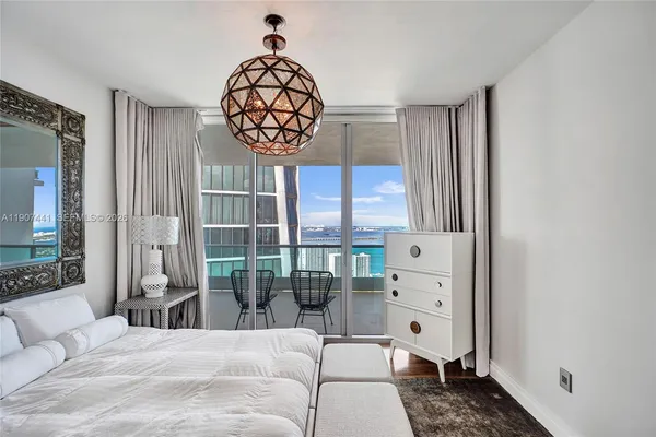 a bedroom with a bed a chandelier and a window