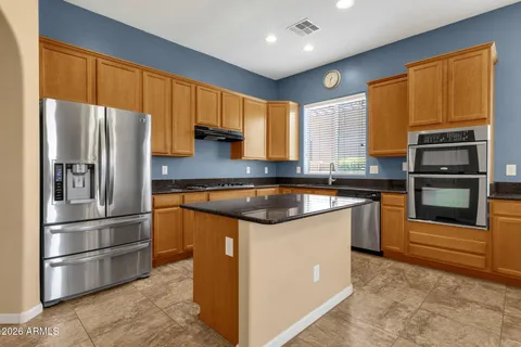 a kitchen with stainless steel appliances granite countertop a refrigerator a sink dishwasher a stove and a refrigerator