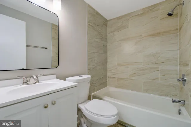 a bathroom with a bathtub shower sink mirror vanity and toilet