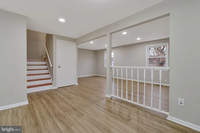a view of an empty room with wooden floor and stairs