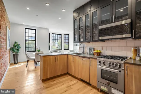 a kitchen with stainless steel appliances granite countertop a refrigerator and a wooden floors