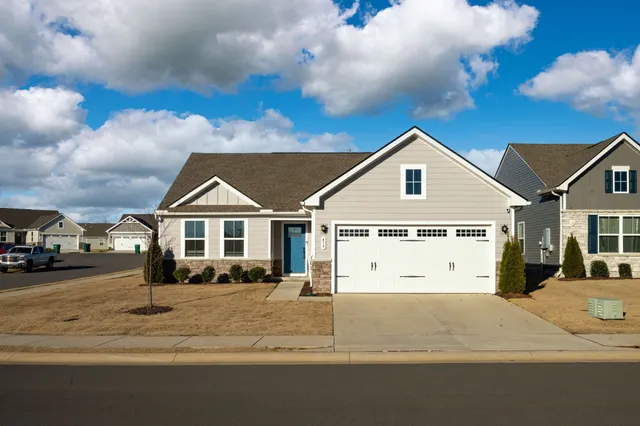 a view of a white house next to a road and covered with buildings
