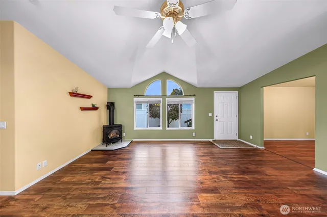 a view of an empty room with a window and wooden floor