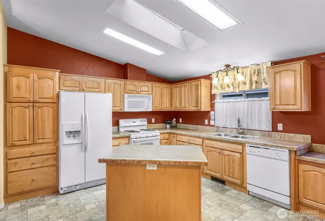 a kitchen with stainless steel appliances granite countertop a refrigerator a sink dishwasher a stove and a refrigerator