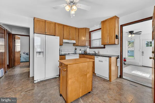 a kitchen with stainless steel appliances granite countertop a refrigerator a sink a stove and white cabinets