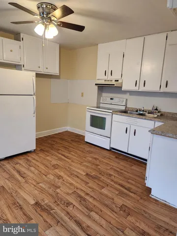 a kitchen with granite countertop white cabinets and white appliances