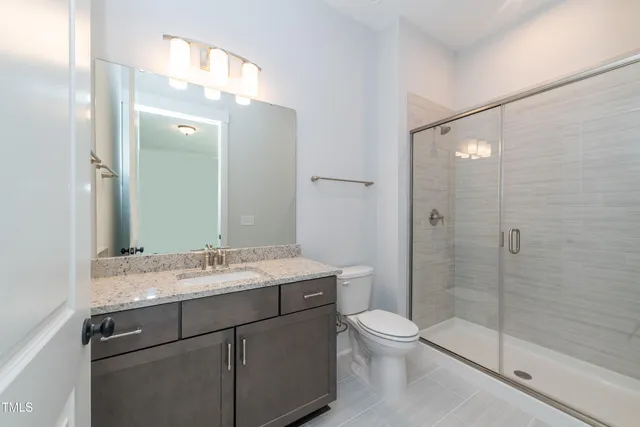 a bathroom with a granite countertop sink toilet a large mirror a shower and vanity
