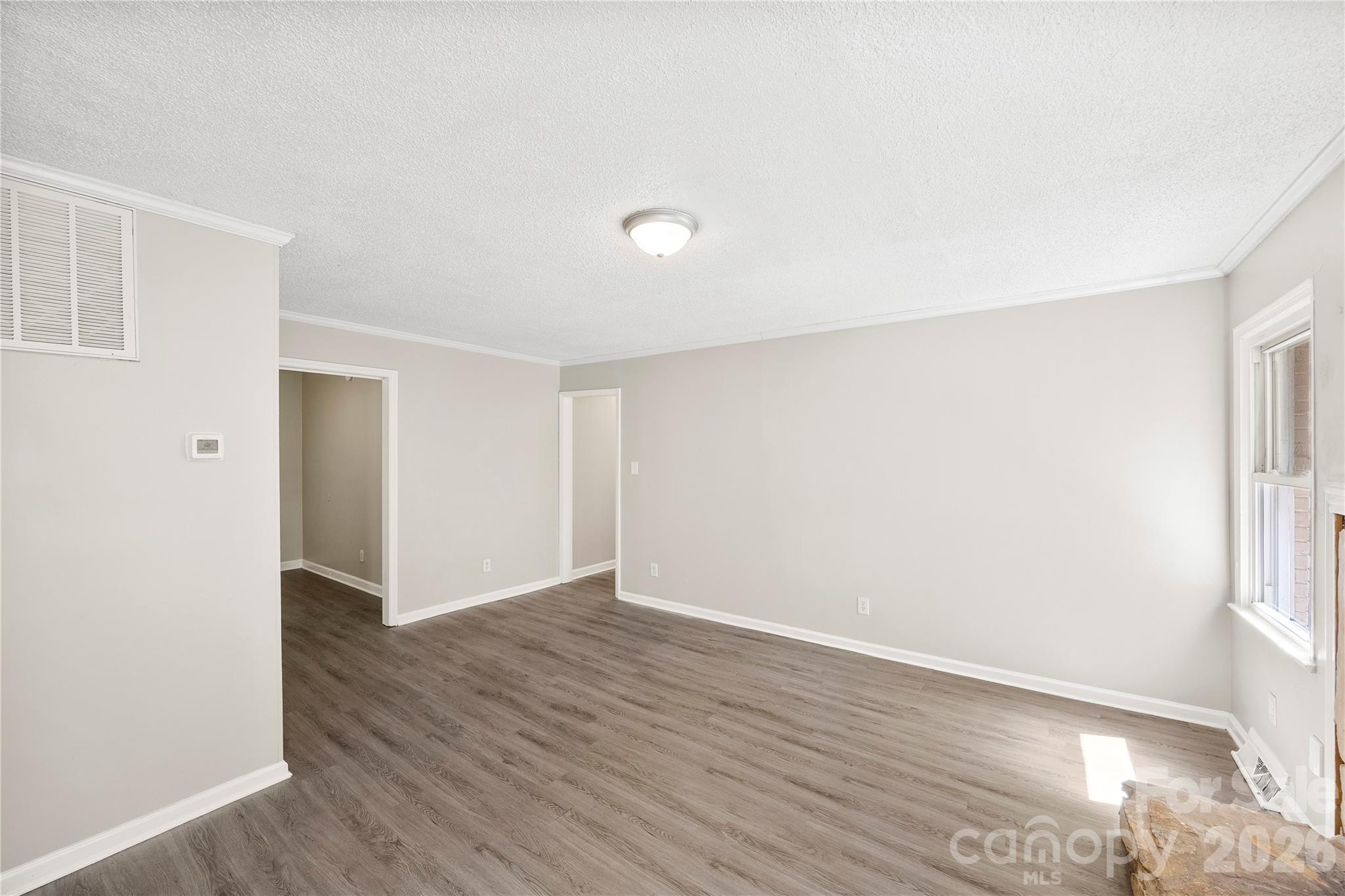 7001 Crossridge Road Charlotte, NC 28214 - Photo 8 of 30 a view of an empty room with wooden floor and a window