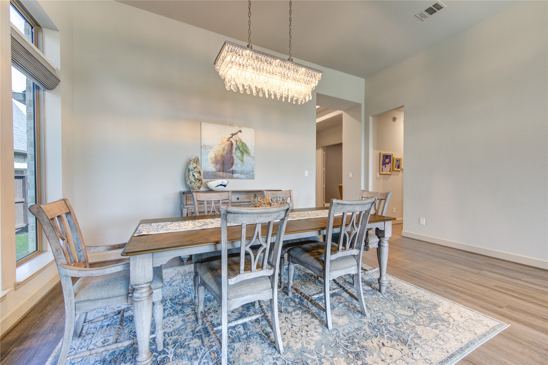 7326 Orangetip Road Katy, TX 77493 - Photo 8 of 43 The formal dining room is a sophisticated space designed for gatherings and celebrations. Featuring high ceilings and wood plank luxury vinyl floors, this room exudes warmth and elegance. A large window allows natural light to pour in, creating a bright and inviting atmosphere.
