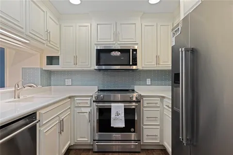 a kitchen with granite countertop white cabinets and stainless steel appliances