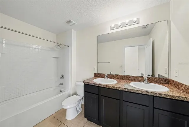 a bathroom with a granite countertop sink mirror toilet and bathtub