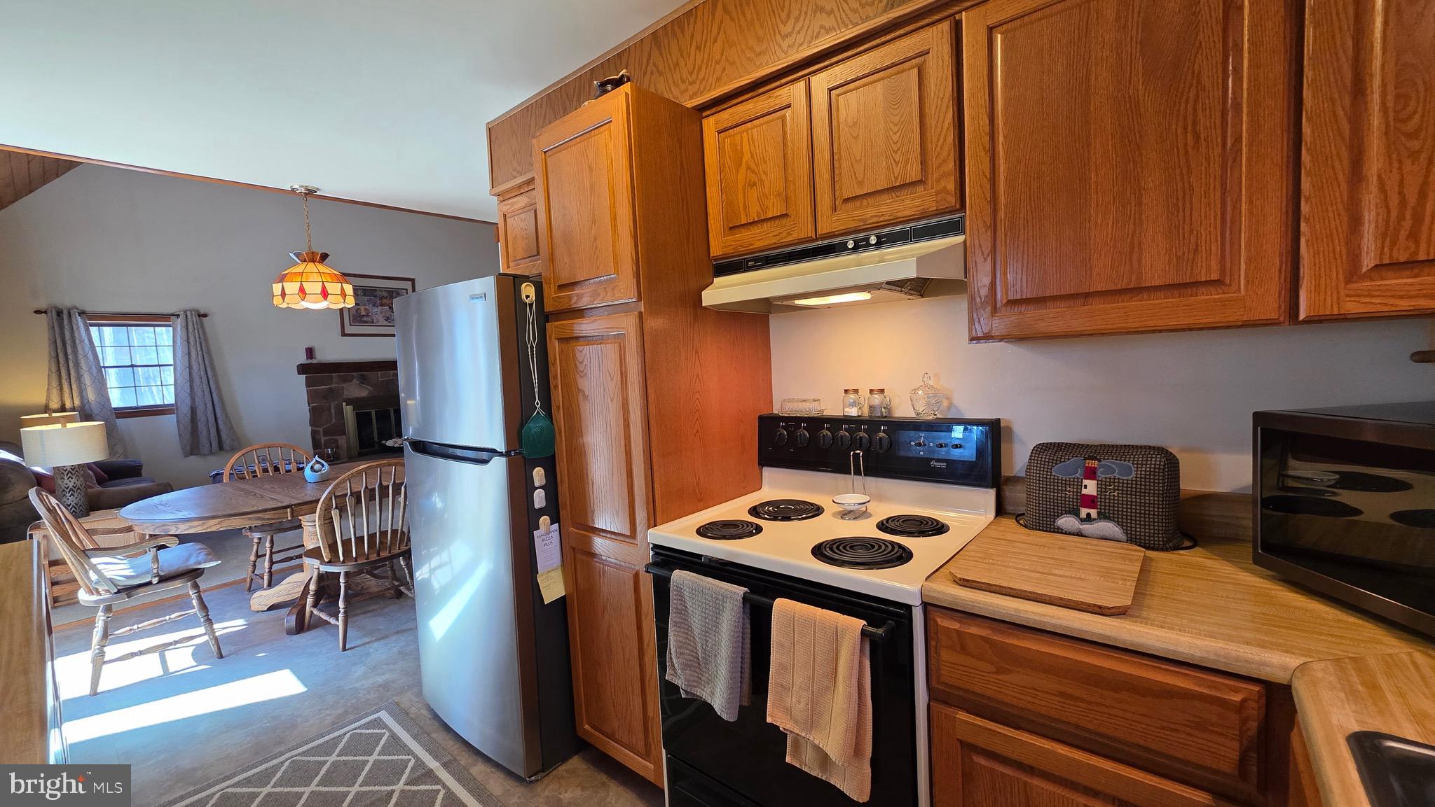 3027 Whitesel Road James Creek, PA 16657 - Photo 10 of 51 a kitchen with stainless steel appliances a stove a refrigerator a sink a dining table and chairs with wooden floor