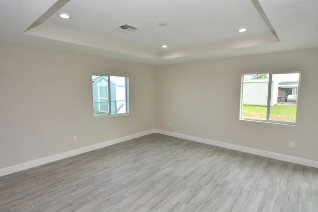 an empty room with wooden floor and windows