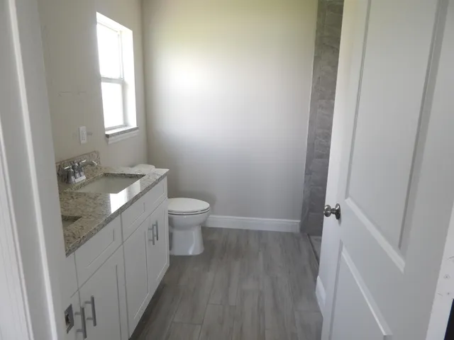 a bathroom with a granite countertop sink toilet and mirror